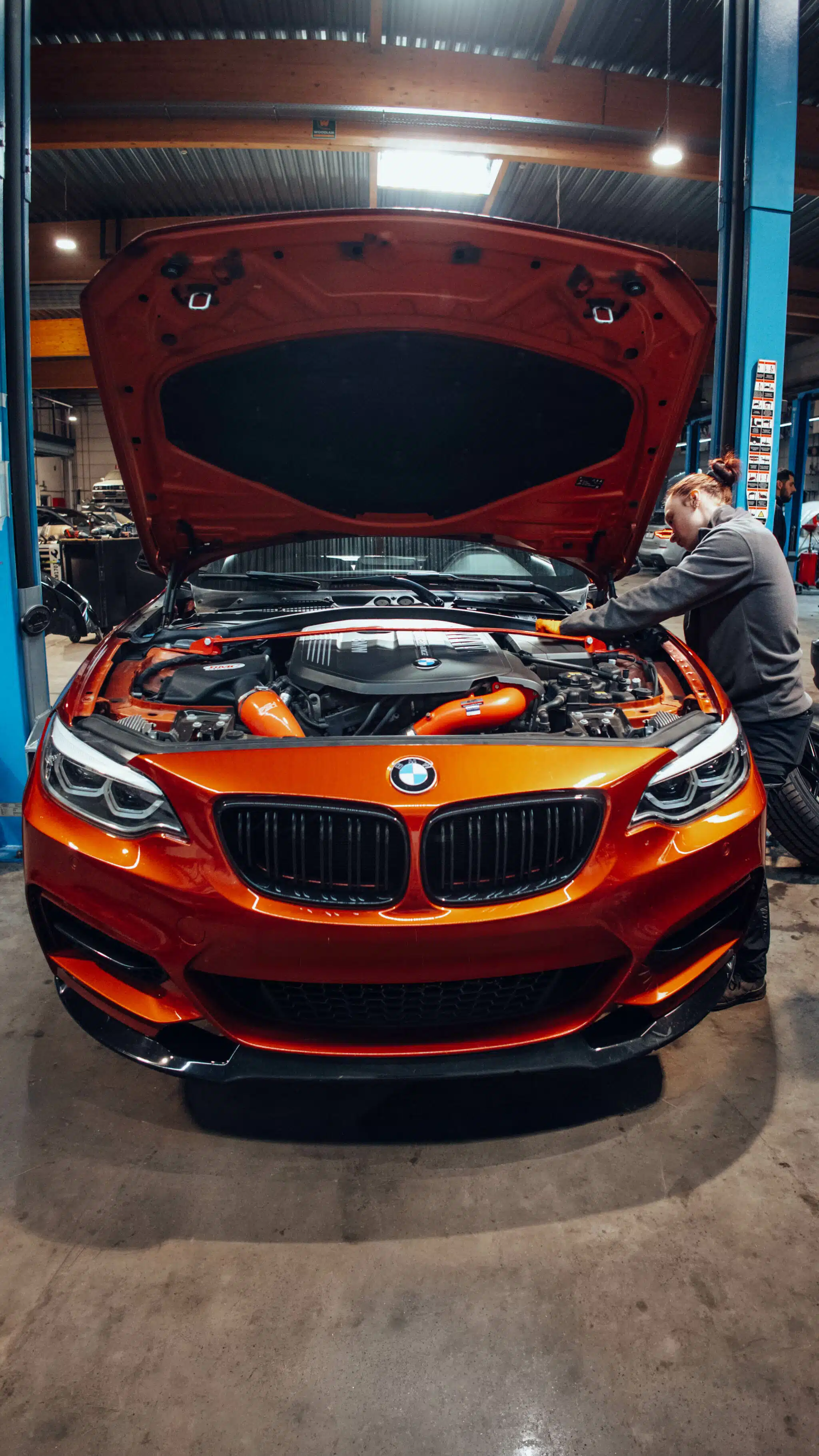 BMW M235i orange capot ouvert en intervention chez Bavarian, réparateur agréé BMW Nivelles Belgique